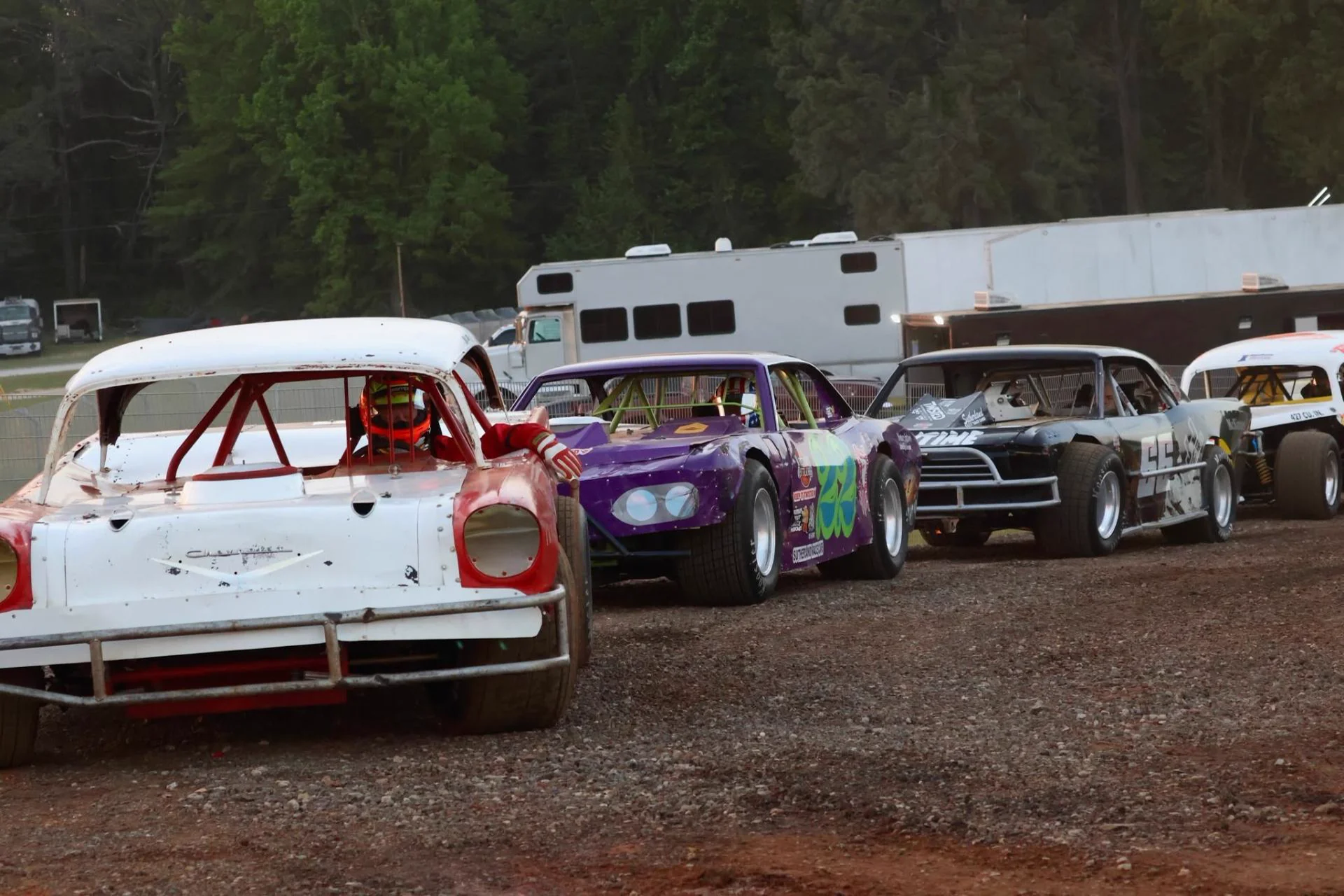 Four vintage Outlaws stock cars lined up in the pits